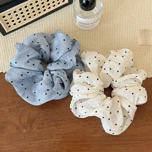 Detail of light blue and creamy white polka dot mesh scrunchies on a textured surface