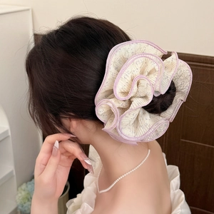 Détail d'un chouchou floral géant en dentelle avec bords plissés roses sur un modèle