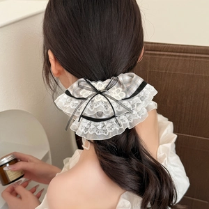 Detail of ballet style lace scrunchie with brown plaid fabric and black ribbon bow tie