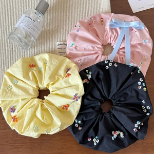 Détail de perles colorées et d'un nœud sur des chouchous en tissu géants de trois couleurs