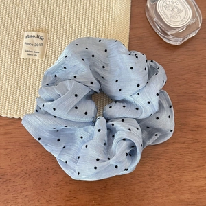 Close-up of light blue polka dot mesh scrunchie on a rustic wooden table setting