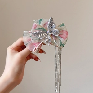 Détail de pince à cheveux nœud en tulle floral rose avec strass brillants et franges métal
