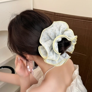 Gros plan sur chouchou en mousseline fleurie bleue avec bords festonnés jaunes en chignon