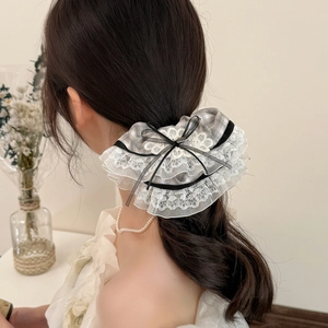 Ballet style plaid scrunchie with white lace edges and black ribbon bow on dark hair