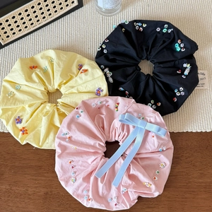Trois chouchous floraux en noir, jaune et rose avec des paillettes de perles colorées