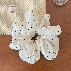Detailed macro view of white tulle hair scrunchie with black polka dots on wooden table