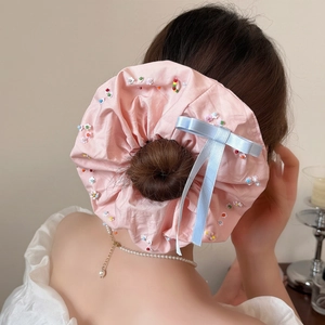 Détail d'un chouchou rose géant orné de perles colorées et d'un nœud en ruban bleu ciel