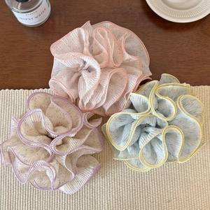 Trois chouchous en dentelle florale rose, violette et jaune sur un tapis tressé