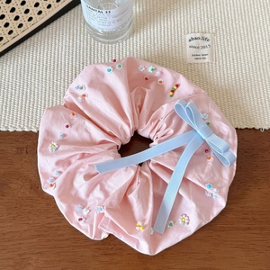 Gros plan détaillé d'un chouchou rose avec perles colorées et un petit nœud bleu doux