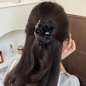 Elegant black bow hair claw clip with rhinestones and center gemstone on hair