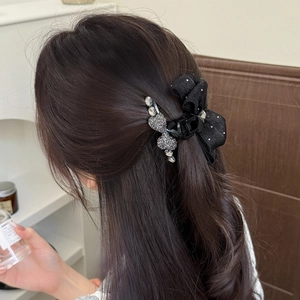 Black polka dot bow hair claw clip with rhinestones worn on long wavy brown hair