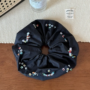 Détail d'un grand chouchou noir duveteux avec des perles colorées sur un bureau rustique
