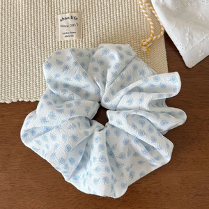 Vue détaillée du chouchou à fleurs bleues en tissu seersucker avec motif floral délicat