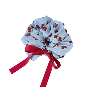 Chouchou fleuri avec ruban en soie rouge sur fond blanc pour femme