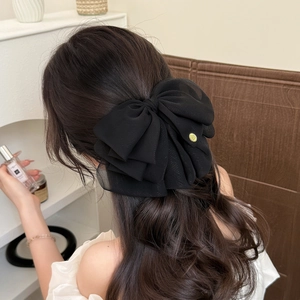 Elegant large black layered chiffon bow hair clip with gold logo on a model's ponytail
