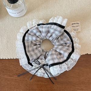 Close-up of ballet-style plaid scrunchie with layered black ribbon and white lace trim