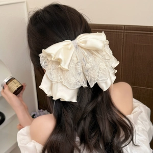 Elegant cream white lace bow hair claw clip with pearl accents on a woman's hair