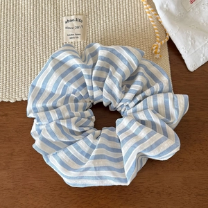 Détail du chouchou à rayures bleues et blanches sur bois foncé avec des accents de lin