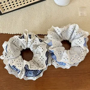 Close-up of four-layer lace and blue plaid scrunchies on a textured wooden surface