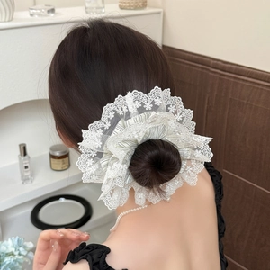 Chouchou rayé bleu surdimensionné avec broderie dentelle sur une coiffure en chignon