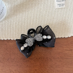 Detail of black bow hair claw with sparkling crystal hearts and rhinestones on soft mesh fabric