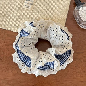 Detail of four-layer lace and blue plaid scrunchie on a rustic wooden surface