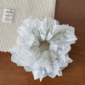 Détail d'un chouchou en dentelle blanche avec tissu à rayures bleues et textures