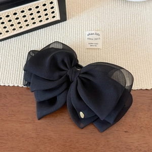 Elegant black layered chiffon bow hair clip with a gold metal tag and banana clip