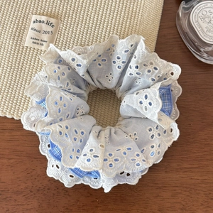 Detail of four-layer lace and blue gingham plaid scrunchie on a rustic wooden table