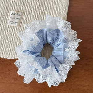 Gros plan d'un chouchou à rayures bleues avec bordure en dentelle fleurie blanche