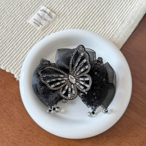 Détail d'une pince à cheveux papillon en résille noire avec des strass étincelants