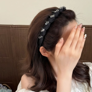 Elegant black wave headband with crystals worn by model with voluminous curly hair