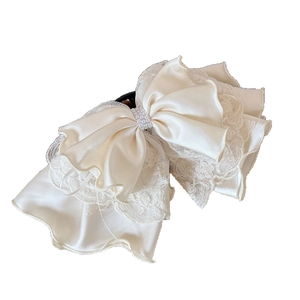 Elegant multi-layer lace bow hair claw with cream satin and pearl accents on white background