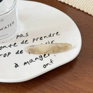 Détail macro d'une barrette feuille en acétate avec texture marbrée sur assiette en céramique