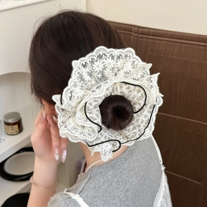 Macro view of white four-layer lace scrunchie with floral embroidery and black trim detail