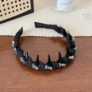 Close-up of black punk style headband with glossy spikes and clear crystal accents