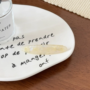 Gros plan d'une barrette en acétate marbré sur un plateau en céramique avec gravure