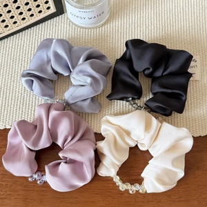 Close-up of silk satin hair scrunchies with bead details in four elegant colors