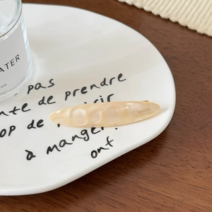 Détail d'une pince à cheveux élégante en acétate sur une assiette décorative blanche
