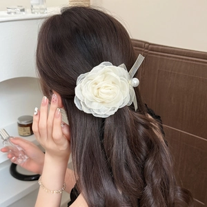 Barrette fleur rose en satin blanc avec perle et ruban sur cheveux bouclés