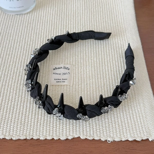 Detail of black woven headband with crystal accents and studs on textured fabric