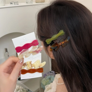 Irregular wavy acetate hair clips in various marble patterns shown with model styling