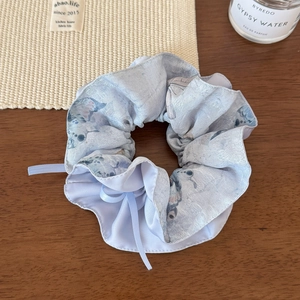 Gros plan d'un chouchou floral bleu clair avec rubans sur une table en bois rustique