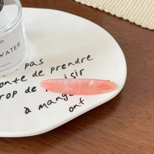 Détail de la barrette en acétate rose marbré avec pince dorée sur platine blanche