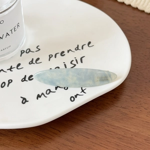 Détail d'une barrette en acétate bleu marbré avec inscription dorée élégante