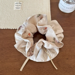 Détail d'un chouchou en satin de soie à fleurs vintage avec rubans sur fond en bois