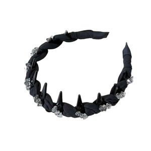 Punk style black wavy headband with crystal accents and sharp cone studs on white background