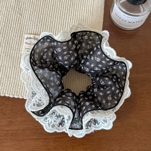 Close-up of four-layer lace scrunchie with paisley pattern and elegant white trim