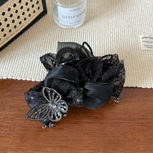 Détail de la pince à cheveux élégante avec nœud en dentelle noire et strass brillants