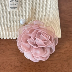 Détail d'une pince à cheveux fleur en mousseline rose avec perle et nœud en ruban